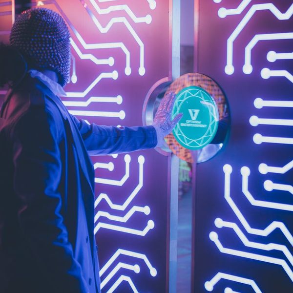 Man stretching his arms toward the crimson neon light